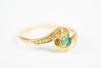a close up of a gold ring with a green stone