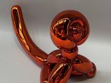 a shiny red balloon shaped like a monkey on a white surface