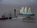 three toy ships and a lighthouse on a table