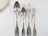 four forks and a spoon sitting on a white table