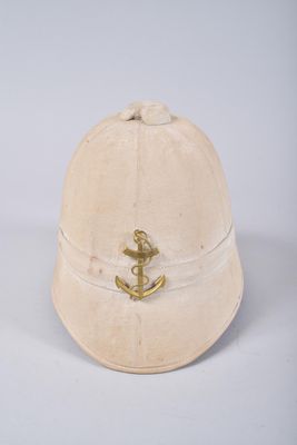 un vieux chapeau orné d'une ancre dorée, posé sur une surface blanche