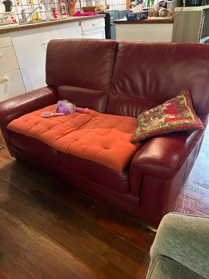a red leather couch with a pillow on it in a living room