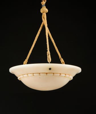 un bol en verre blanc suspendu à une corde sur fond noir