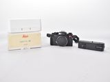 a black camera and a white box on a white surface