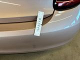 the rear end of a white car with a sticker on it ' s bumper