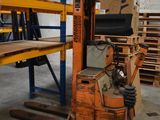 une photo d'un chariot élévateur dans un entrepôt, avec des palettes et des cartons