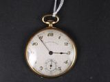 a gold pocket watch hanging from a string on a black surface