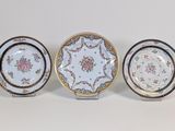 three plates with floral designs on them sitting on a white surface