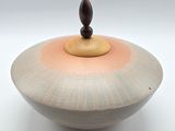 a small bowl with a wooden lid on a white surface