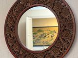 a round mirror hanging on the wall above a sink