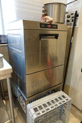 a silver dishwasher sitting on top of a metal rack in a kitchen