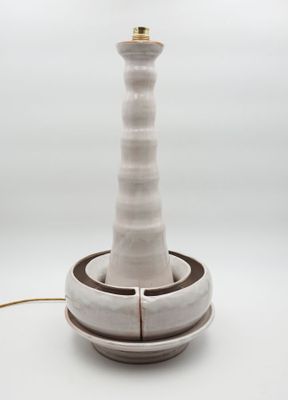 white ceramic table lamp with a brown base and a light bulb on top of it