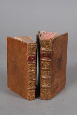 two old books sitting side by side on a gray surface