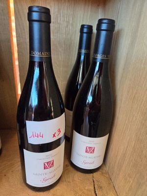 trois bouteilles de vin rouge sont posées sur une étagère dans une cave à vin