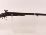 un vieux fusil au canon en bois, posé sur un socle transparent