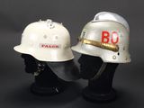 pair of firemen ' s helmets on display on a black background