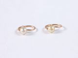 two gold rings with pearls on them on a white surface
