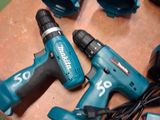 five corded drillers sitting on a table next to a charger
