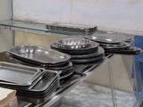 many trays and pans sitting on a shelf in a kitchen