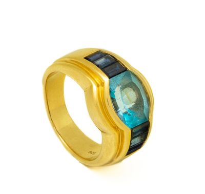 gros plan d'une bague en or avec une pierre bleue
