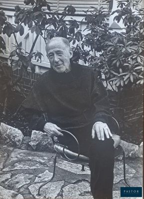 black and white photograph of a man sitting on a bench in front of a tree