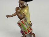 figurine of a monkey playing a drum with a hat on