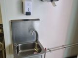 un évier dans un coin de la cuisine, avec un distributeur d'eau fixé au mur