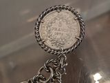 a silver chain bracelet with a coin on it