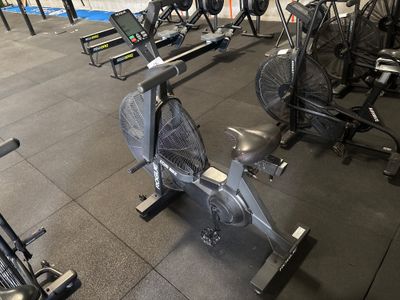 une salle de sport équipée d'une rangée de vélos d'appartement et d'un ventilateur