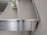 stainless steel sink in a public restroom with a bottle of water on top of it