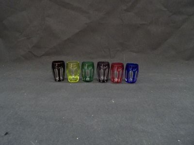 several different colored shot glasses lined up in a row on a gray surface