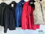 quatre vestes accrochées au mur, à côté d'un porte-manteau