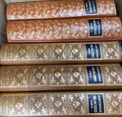 Plusieurs vieux livres sont empilés dans une boîte posée sur une table