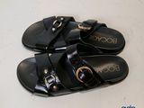 pair of black sandals with gold buckles on them on a white surface