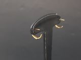 a close up of a pair of gold hoop earrings on a black stand