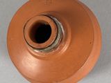 a brown vase with a hole in it on a white surface