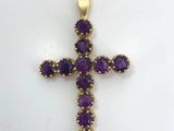 an amethorate cross pendant with purple stones on a white background