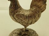 a silver chicken on a silver plate on a white table