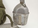 a metal container with a metal lid next to a green bag