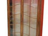 une armoire en bois avec des portes vitrées et un mur rouge