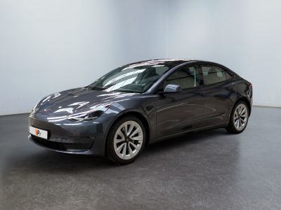 La Tesla Model 3 est garée dans une pièce au sol noir.
