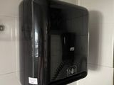 un distributeur de savon noir fixé au mur dans une salle de bains