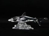 clear glass figurine of a shark and a fish on a black background