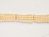 a close up of a bracelet with pearls on a white surface
