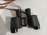 an old pair of binoculars on a white surface with a brown strap