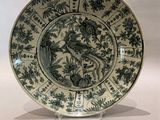 une assiette ornée d'un oiseau, posée sur un socle