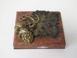 brass figurine of grapes and leaves on a wooden box