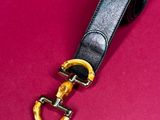 a black leather belt with a gold buckle on a pink background