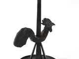 a black rooster statue on a stand on a white background
