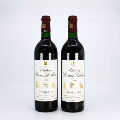 two bottles of red wine sitting next to each other on a white surface